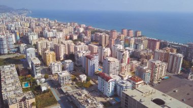 Güneşli bir yaz gününde mavi sonsuz okyanus kıyısındaki büyük şehir üzerinde harika bir insansız hava aracı uçuşu. - Sanat. Mavi gökyüzü arka planındaki caddelerin ve binaların havası.