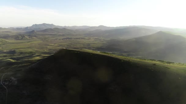 Impresionante vista aérea de la colina verde y el valle sobre el fondo azul del cielo. Le dispararon. Volando por encima de la pequeña ciudad y las montañas verdes . — Vídeos de Stock