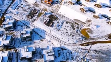 Güneşli bir kış gününde karla kaplı şehrin sanayi bölgesinde uçmak. Yolculuk. Kışın havadan güzel evler ve şantiye..