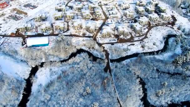 River flows near small village in winter, aerial landscape, cold weather concept. Journey. Breathtaking view of cold countryside area near coniferous forest. — ストック動画