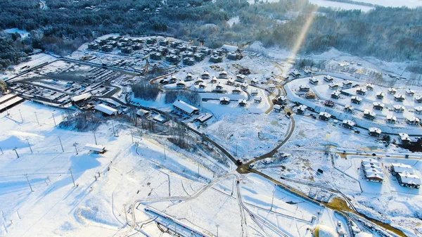 Vista aérea de un pequeño pueblo entre los campos y bosques en invierno. Viaje. Invierno paisaje pintoresco, campo cubierto de nieve y árboles en el campo . — Foto de Stock