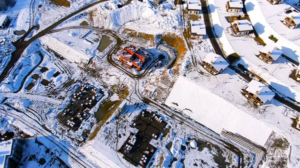Vliegen over het industriegebied van de stad bedekt met sneeuw op een zonnige winterdag. Reis. Luchtfoto van prachtige huizen en de bouwplaats in de winter. — Stockfoto
