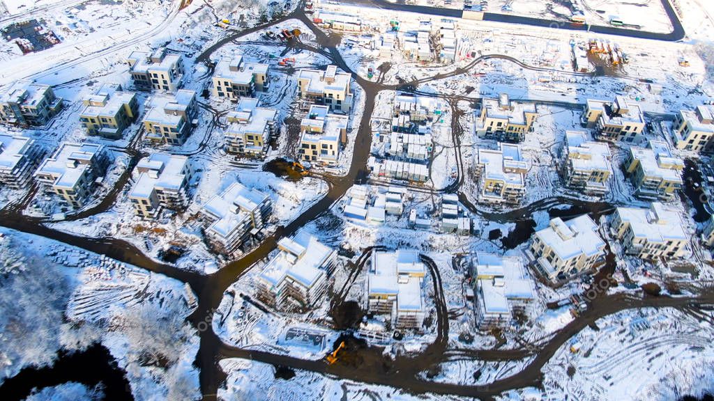 Aerial view of winter industrial cityscape from air. Journey. Snowy landscape at cold season of a town in forested area, snow scenery landmark.