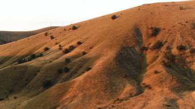 Sonbahar manzarası, dağ yamaçlarında dramatik günbatımı. Vuruldu. Mavi gökyüzü arka planındaki tepeleri kaplayan nadir ormanlar.
