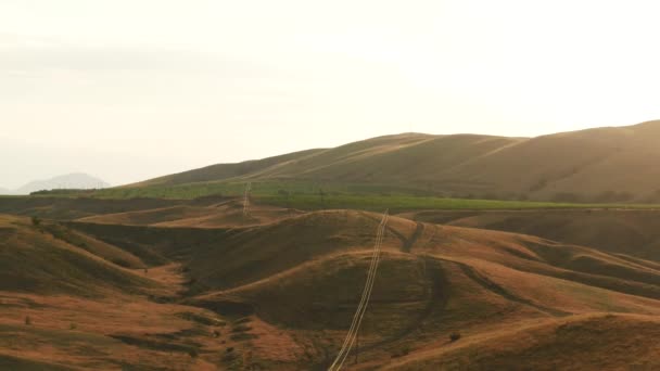 Yazın gökyüzüne karşı çalılarla ve büyük yeşil tarım arazileriyle kaplı heyecan verici kırmızı tepelerin havadan görünüşü. İnanılmaz renkli bir manzara. — Stok video