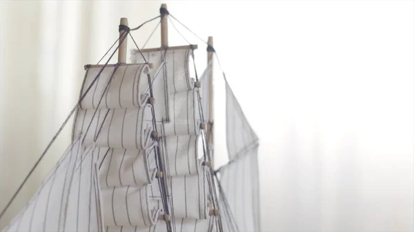 Wooden ship toy model standing on a wooden table in light room, hobby concept. Stock footage. Close up of the sailing ship small figure.