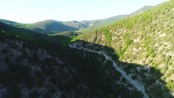 Aerial view of road going through a green mountains covered with shrubs and grass against blue sky in subber day. Shot. Beautiful view from above — Vídeo de Stock