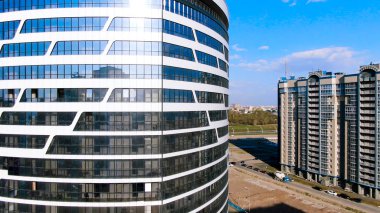 Mavi bulutlu arka planda cam cepheli ofis binası. Yolculuk. Konut alanı yakınlarındaki modern iş merkezinin havası.