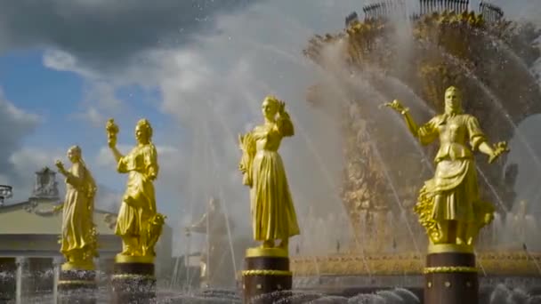 분수 뒤에 금박을 입힌 조각상들이 있습니다. 행동. 커다란 분수에 물을 튀기는 모습을 배경으로 아름다운 황금빛 여성 상이 펼쳐지고 있다 — 비디오