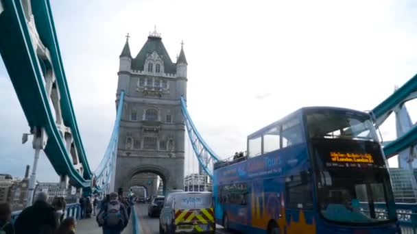 Londres, Gran Bretaña-septiembre de 2019: Antiguo puente europeo con torre arquitectónica sobre fondo celeste. Acción. Vista desde abajo en la torre del puente antiguo con autobuses de paso y turistas a pie — Vídeo de stock