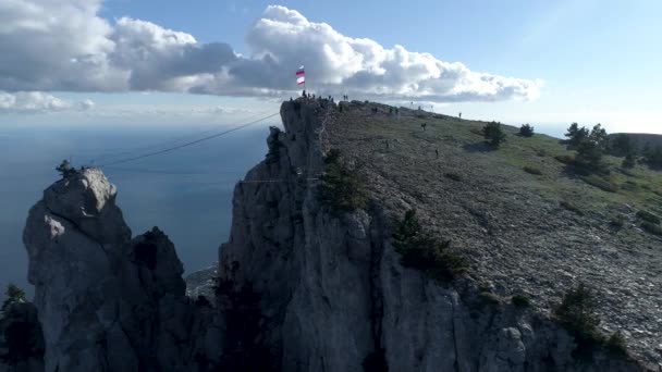 Vista aerea mozzafiato della ripida scogliera vicino al mare blu con funivia e persone che camminano su sfondo cielo nuvoloso. Gli hanno sparato. Funicolare al pendio della montagna, concetto di trasporto . — Video Stock