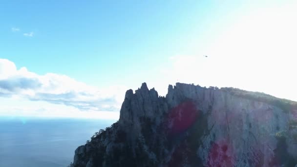 Luchtfoto van steile bergen en kabelbaan met mensen aan de rand. Neergeschoten. Adembenemende zeegezicht met rotsen en blauwe bewolkte lucht op de achtergrond. — Stockvideo