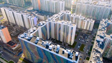 Şehrin yeni bölgesinde renkli cepheli modern yeni konut binaları, banliyö konseptinin genişlemesi. Hareket. Yüksek yeni evlerin, altyapının ve gelişimin havadan görünüşü.