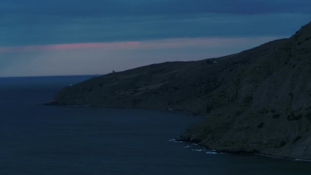 Bergrotsen in de Stille Oceaan in een regenachtige avond. Neergeschoten. Luchtfoto van regenwolken boven het oceaanoppervlak, adembenemend landschap met groene heuvels. — Stockvideo