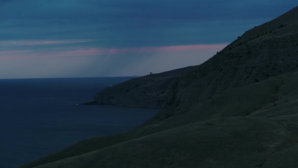 Blaue Wolken bei stürmischem Wetter am Meer in der Nähe grüner Hügel. Schuss. Antenne des Regens, der im Meer an den grünen Berghängen niedergeht. — Stockvideo