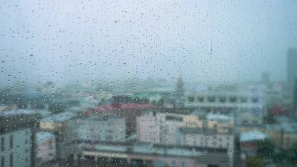 La pluie tombe sur un verre avec un fond. Images d'archives. Des gouttes de pluie sur la fenêtre sur le fond de la ville — Video