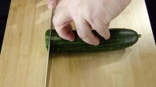 Trancher les légumes avec un couteau pour la cuisson. Images d'archives. Gros plan d'un chef coupe un concombre — Video