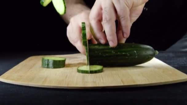 Fatiar legumes com uma faca para cozinhar e fechar o pão de gergelim preto para hambúrguer. Filmagem de estoque. Cozinhar um hambúrguer — Vídeo de Stock