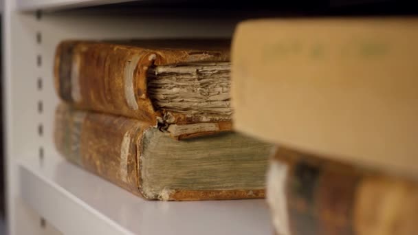Experte holt ein altes Buch aus dem Regal. Archivmaterial. eine antike Reliquie, die von behandschuhten Händen genommen wurde — Stockvideo