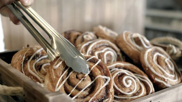 In the grocery store the seller takes one bun for the buyer. Stock footage. A sweet dessert made of puff pastry cooking — Stock Photo, Image