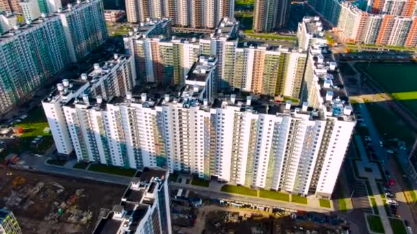 Bouwplaats met nieuwe residentiële hoge gebouwen in de buurt van groen veld op een zomerse zonnige dag. Beweging. Luchtfoto van de moderne wijk van de stad. — Stockvideo
