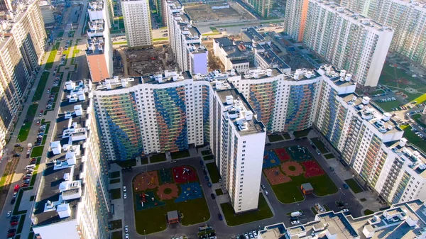 Vista aerea degli edifici a più piani, blocco di appartamenti, parchi giochi all'interno del cortile. Mozione. Volare sopra le nuove case colorate e strade con auto parcheggiate . — Foto Stock