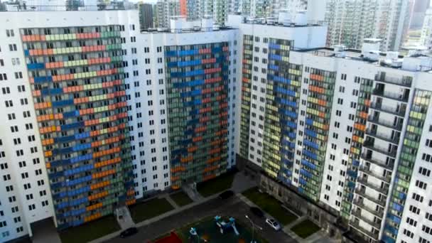 Im Sommer fliegen bunte Fassaden über die Wohnhäuser. Bewegung. Antenne der weißen Gebäude und Innenhof mit geparkten Autos. — Stockvideo