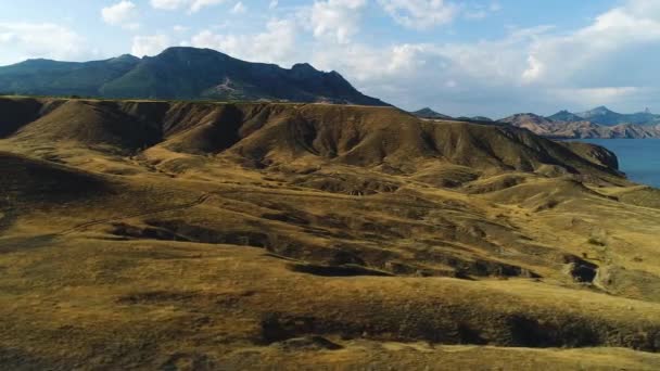 Vista panorâmica das montanhas costeiras do Mar Negro e colinas amarelas em um dia ensolarado de outono, caminhadas e conceito de natureza. Atingido. Ar de amarelo secou a costa do penhasco no fundo azul do céu nublado . — Vídeo de Stock