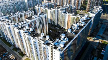 Güneşli bir yaz gününde renkli cepheli yeni binalar inşa ediliyor. Hareket. Şehrin uyku alanındaki yeni bölgenin havadan görüntüsü..