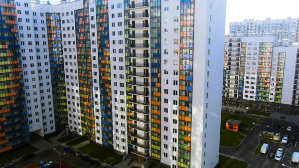 Воздушный пролет строительства многоквартирных домов в спальном районе большого города. Движение. Многоэтажный жилой дом с синими, оранжевыми, зелеными и желтыми стеклянными балконами . — стоковое фото
