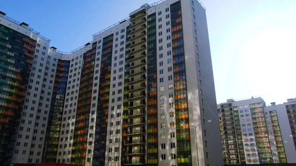 Воздушный пролет строительства многоквартирных домов в спальном районе большого города. Движение. Многоэтажный жилой дом с синими, оранжевыми, зелеными и желтыми стеклянными балконами . — стоковое фото