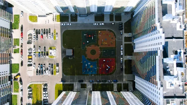 Aerial view of tall skyscrapers with colorful facades with parking space for cars and a children playground in the yard. Motion. Concept of afordable apartment buildings. — Stock Photo, Image