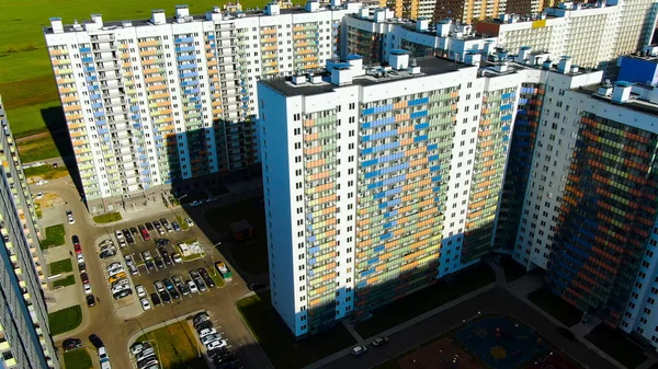 Renkli cepheli gökdelenler, arabalar için park yeri ve bahçesinde çocuk parkı olan gökdelenler. Hareket. Uygun apartman konsepti.