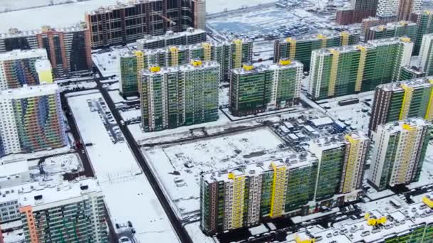 Aerial view of modern city with tall buildings, parked and moving cars along streets covered by snow. Motion. Urban cityscape, view from above of bright colorful houses. — Stock Video