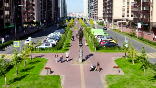 Εναέρια των ανθρώπων που περπατούν στο πράσινο δρομάκι στο δρόμο της θερινής πόλης. Κίνηση. Πετώντας κατά μήκος του δρόμου με κτίρια, αυτοκίνητα, και μονοπάτι. — Αρχείο Βίντεο