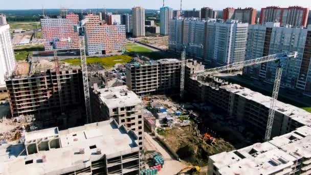 Zicht vanuit de lucht op flatgebouwen op bouwplaats met vier werkkranen. Beweging. Het proces van de ontwikkeling van nieuwe stadsdelen en huizen in aanbouw. — Stockvideo