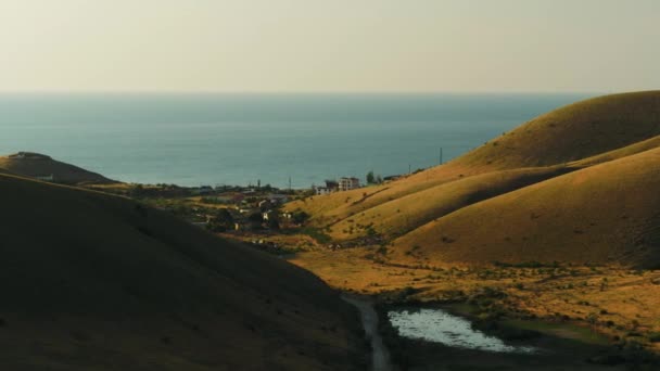 Vista superior del pueblo cerca del mar cerca de las colinas. Le dispararon. Hermoso día soleado en el pueblo junto al mar en otoño — Vídeos de Stock