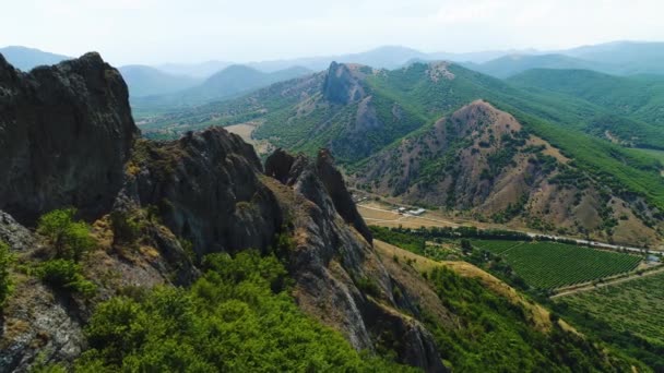 夏の日に集落のある山岳地帯のトップビュー。撃たれた夏の日に山の緑の草の間の村の民家 — ストック動画