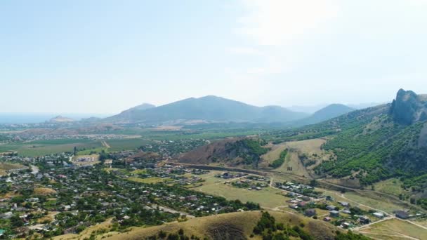 Village parmi l'herbe verte dans les montagnes un jour d'été. Fusillade. Vue de dessus de la vue naturelle pittoresque par une journée ensoleillée — Video