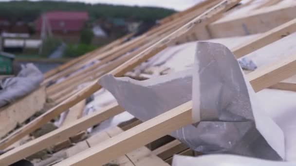 Vista lateral do telhado inacabado coberto por material de cobertura branco com efeito à prova de fogo. Clipe. Close up de tábuas de madeira e tecido branco no canteiro de obras . — Vídeo de Stock