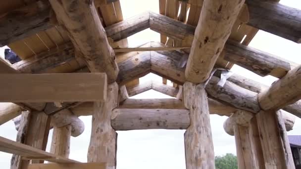 Bottom view of a new home under construction and its unfinished roof on bright cloudy sky background. Clip. View inside of the house made of timber. — Stock Video