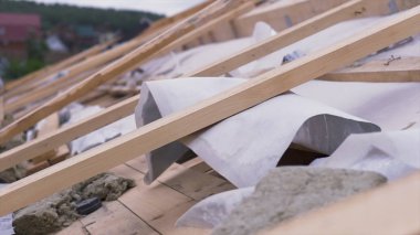 Yangına dayanıklı beyaz çatı malzemeleriyle kaplı bitmemiş çatı manzarası. Şarjör. İnşaat alanındaki tahtaları ve beyaz kumaşı kapatın..