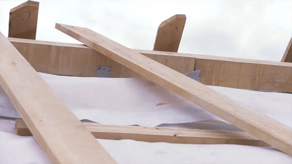 Close up de telhado de madeira inacabado de uma nova casa no local de construção com pano de proteção branco acenando ao vento, conceito de carpintaria. Clipe. Partes de novo edifício ecológico . — Fotografia de Stock