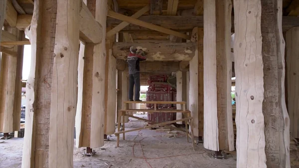 Broyage par une polisseuse de rondins de pin sur le chantier de construction d'une maison neuve. Clip. Nettoyage du bois du champignon et de la moisissure sur le chantier . — Photo