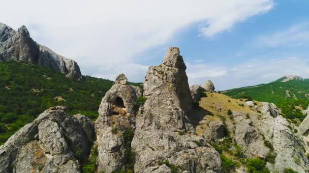 Vista superior de cumes de rocha no fundo de montanhas verdes e céu azul. Atingido. Bela paisagem montanhosa com maciços de rocha e grama verde no fundo do céu — Vídeo de Stock