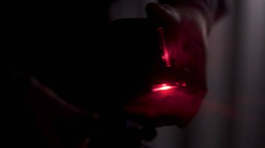 Karanlık odada seviye ölçümü için kırmızı lazer hattı, inşaat aletleri ve ekipman konsepti. Stok görüntüleri. Karanlıkta lazer seviyesini ayarlayan elleri kapat.