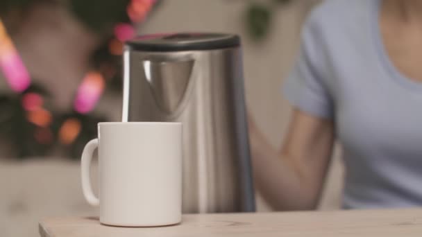 Primer plano de las manos de las mujeres vertiendo té sobre el fondo de las luces. Imágenes de archivo. La joven se prepara una taza de té. Mujer hace té sobre fondo de luces borrosas — Vídeos de Stock