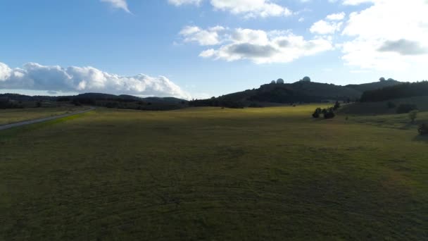 Widok z góry pola trawy na wzgórzach w słoneczny dzień. Postrzelony. Piękny widok na malowniczą przyrodę w oddali widać potężne teleskopy gwiazdowe — Wideo stockowe