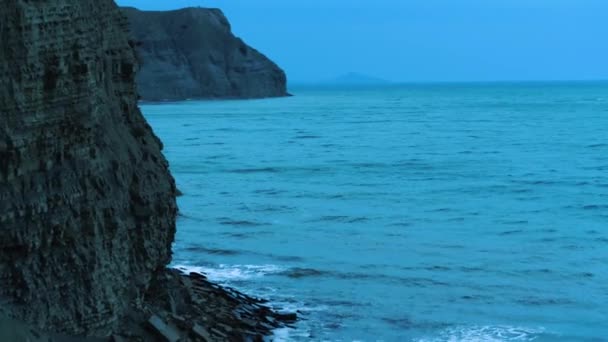 Flygfoto över havet nära kusten. Skjuten. Ovanifrån av de höga klipporna nära havet. En rasande havsbrytande vågor på stenar — Stockvideo