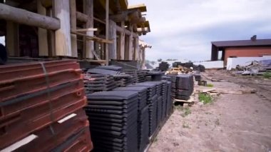 İnşaat alanında yerde yatan beton çatı kiremitlerini kapatın. Şarjör. Yeni ahşap bina için çatı malzemesi..